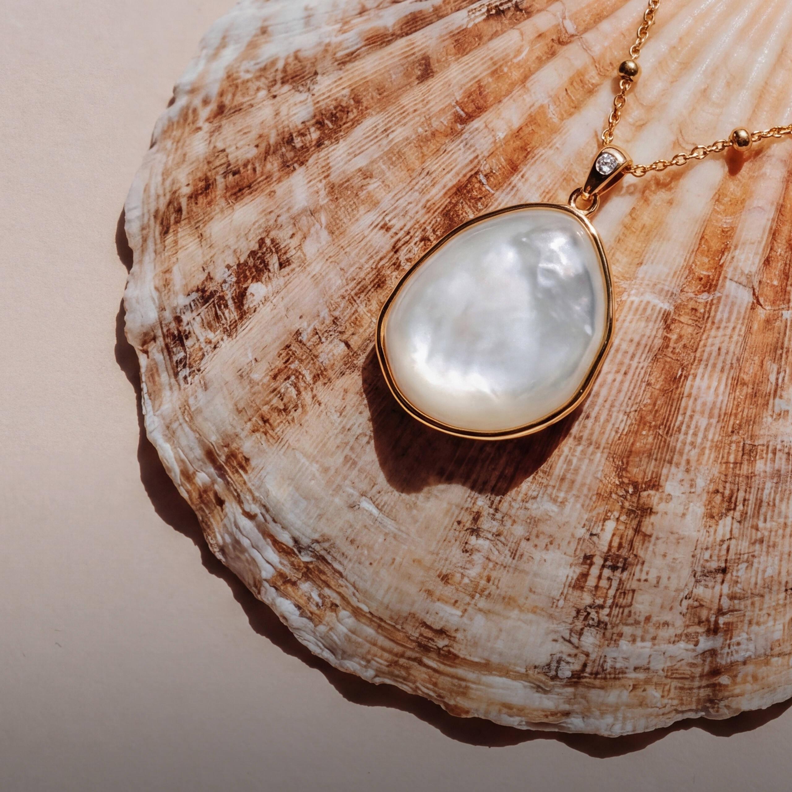 Gold and pearl pendant necklace styled on a seashell