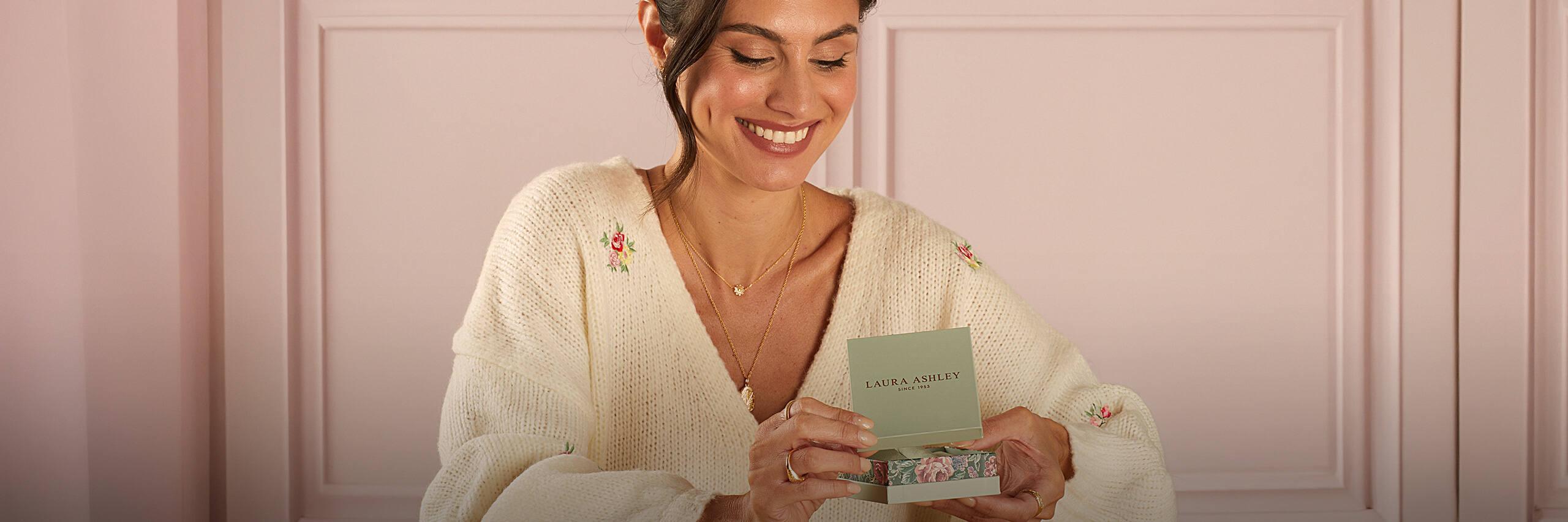 Woman wearing Laura Ashley jewellery and holding a Laura Ashley gift box, showcasing the brand's timeless, elegant designs.