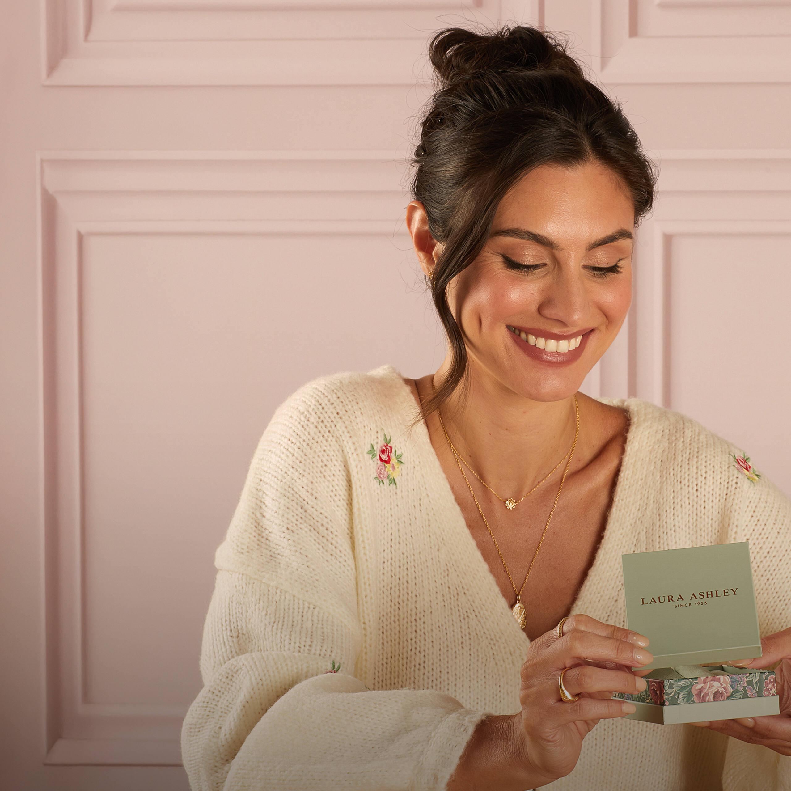 Woman wearing Laura Ashley jewellery and holding a Laura Ashley gift box, showcasing the brand's timeless, elegant designs.